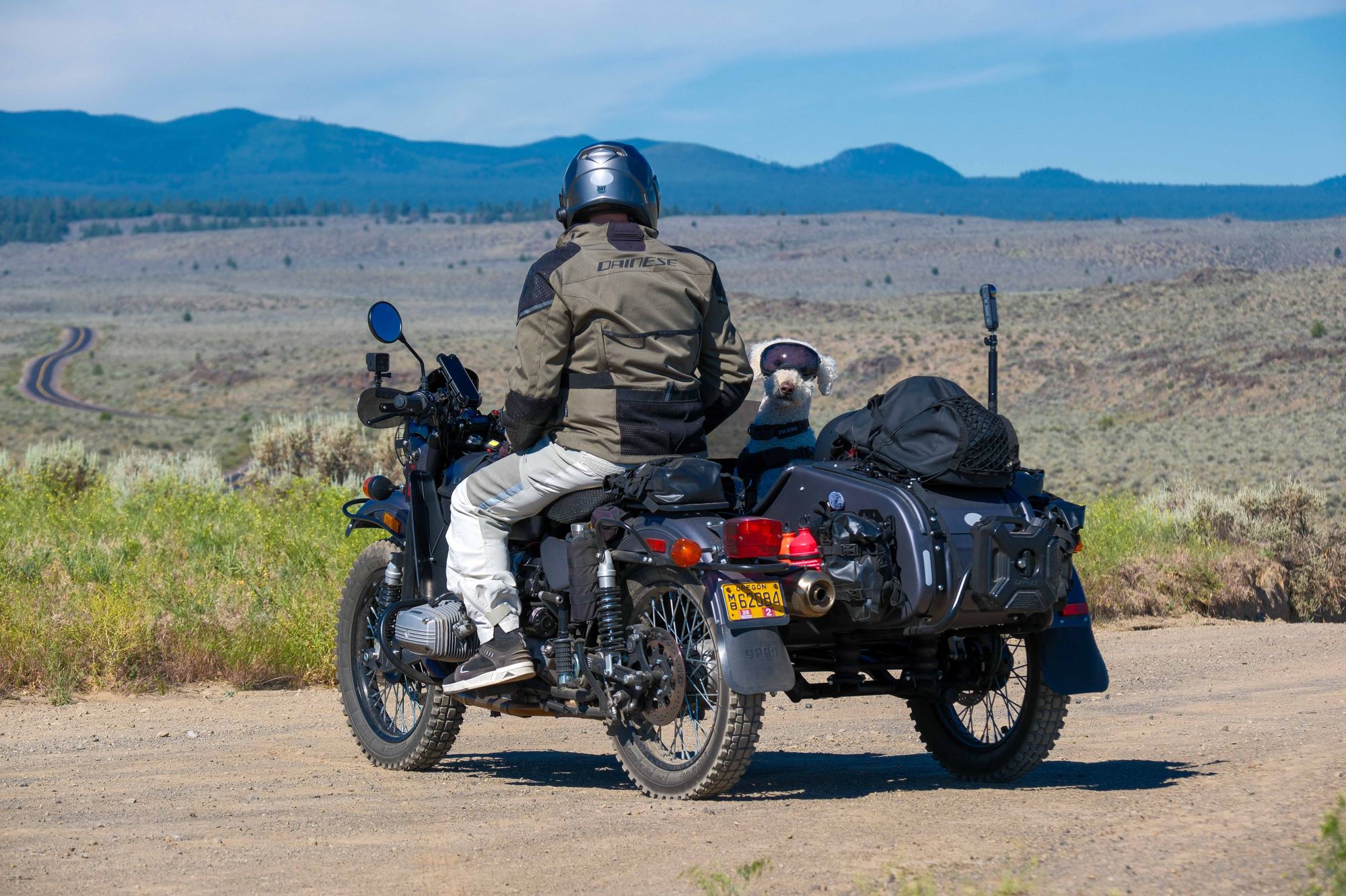 Kalinka loaded for the road, seen from behind on a gravel track in the high desert.